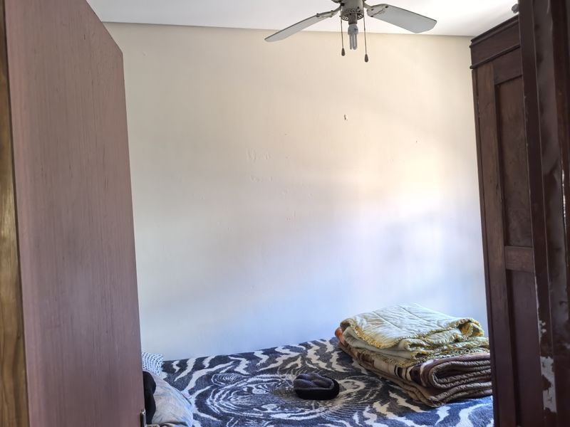 A bedroom featuring a ceiling fan, viewed through a doorway.