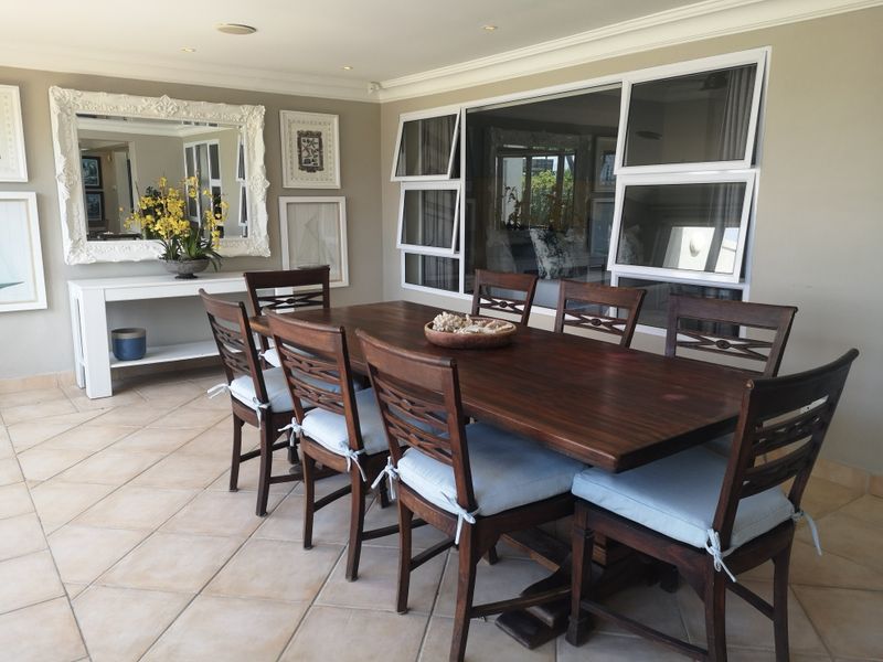 A well-maintained dining room featuring tiled flooring, crown molding, and large top-hung windows that provide ample natural light.