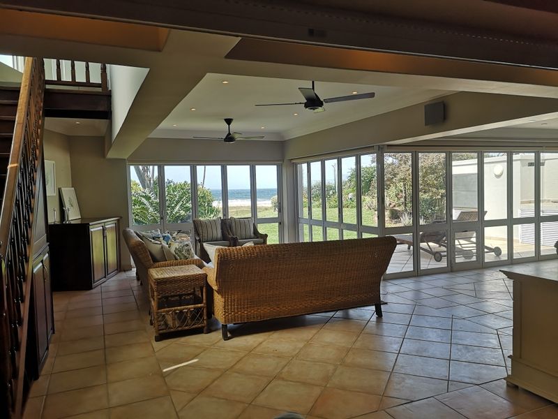 Spacious open-plan living area featuring tiled floors, recessed lighting, and expansive glass folding doors that provide seamless indoor-outdoor flow and ocean views.