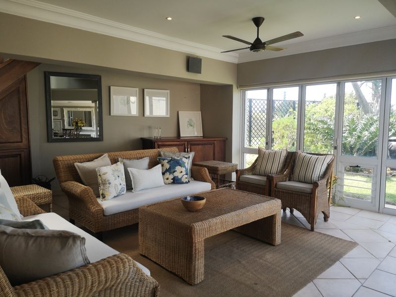 A comfortable living room featuring tiled flooring, recessed lighting, a ceiling fan, and large sliding glass doors that provide access to the garden.