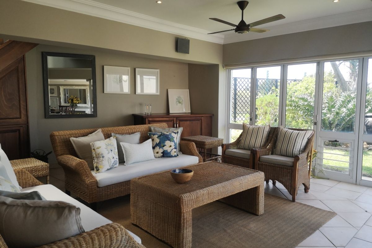 A comfortable living room featuring tiled flooring, recessed lighting, a ceiling fan, and large sliding glass doors that provide access to the garden.