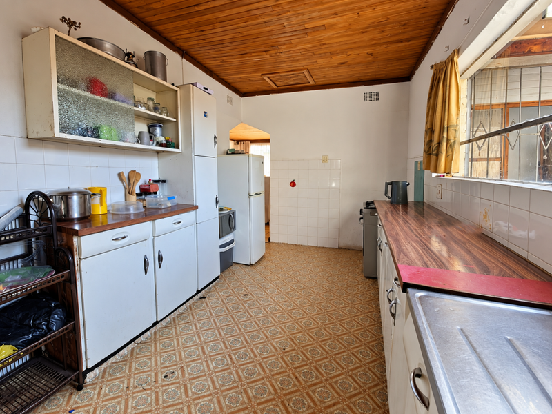 A dated kitchen featuring timber ceilings, laminate countertops, and original cabinetry, offering significant potential for a modern renovation and layout update.