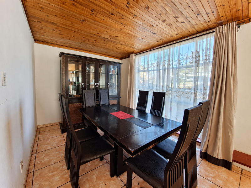 Dining room featuring a warm timber tongue and groove ceiling, ceramic tiled flooring, and a large window with natural light.