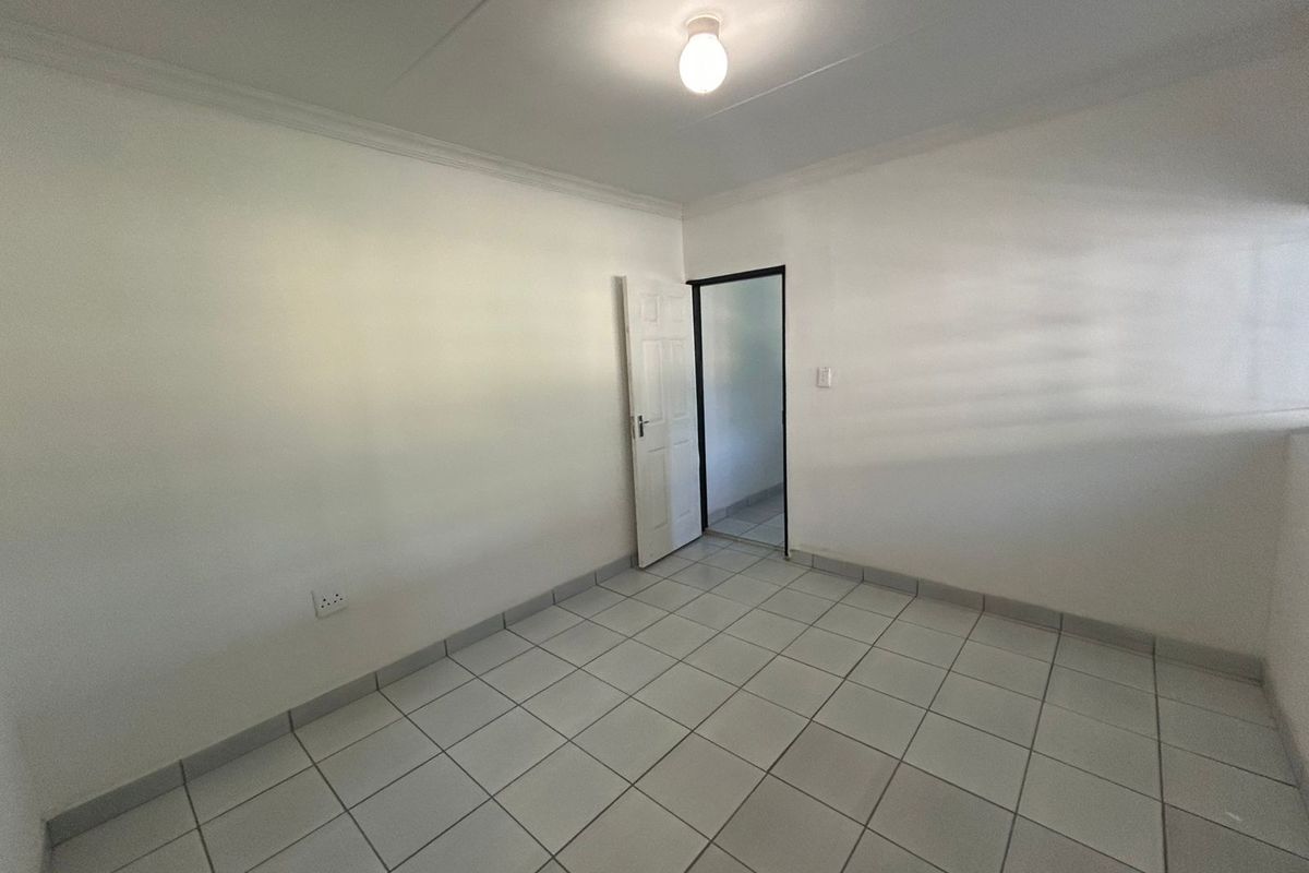 A clean, empty bedroom featuring neutral tiled flooring, white walls, and a coved ceiling, providing a versatile blank canvas for interior design.