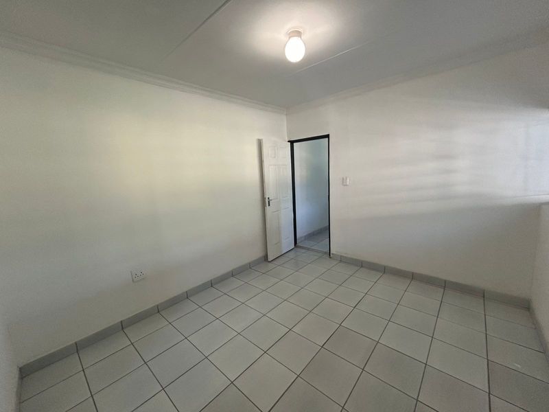 A clean, empty bedroom featuring neutral tiled flooring, white walls, and a coved ceiling, providing a versatile blank canvas for interior design.