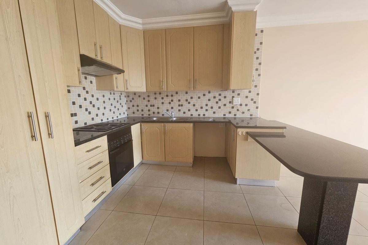 A functional kitchen featuring light wood cabinetry, granite countertops, a mosaic tile backsplash, and a convenient breakfast bar extension.