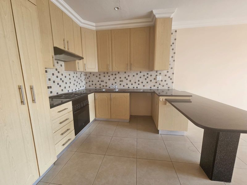 A functional kitchen featuring light wood cabinetry, granite countertops, a mosaic tile backsplash, and a convenient breakfast bar extension.
