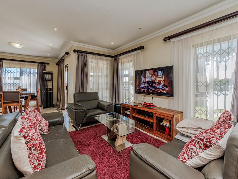 Spacious open-plan living and dining area featuring tiled floors, recessed lighting, and large windows with security gates, creating a bright and functional living space.