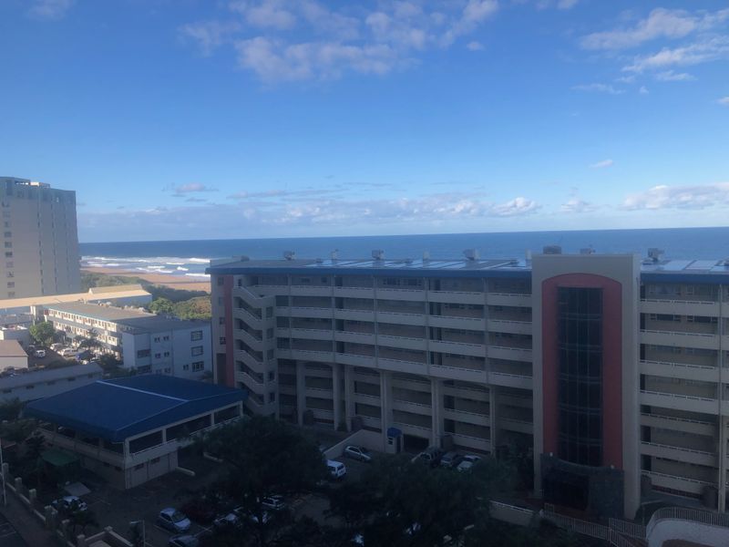 Elevated coastal view overlooking neighboring apartment buildings and the ocean horizon.