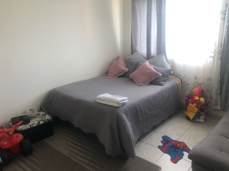 A functional bedroom featuring tiled flooring and natural light from the window, providing a comfortable space for rest.