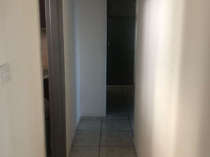 A simple, functional hallway featuring tiled flooring and neutral walls, providing access to various rooms within the apartment.