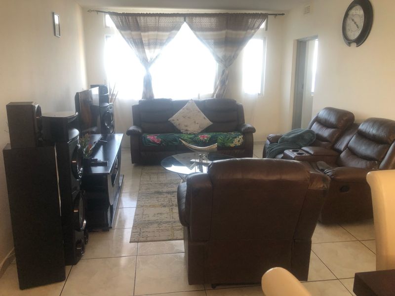 A living room featuring tiled flooring and a large window, providing a functional space for relaxation.