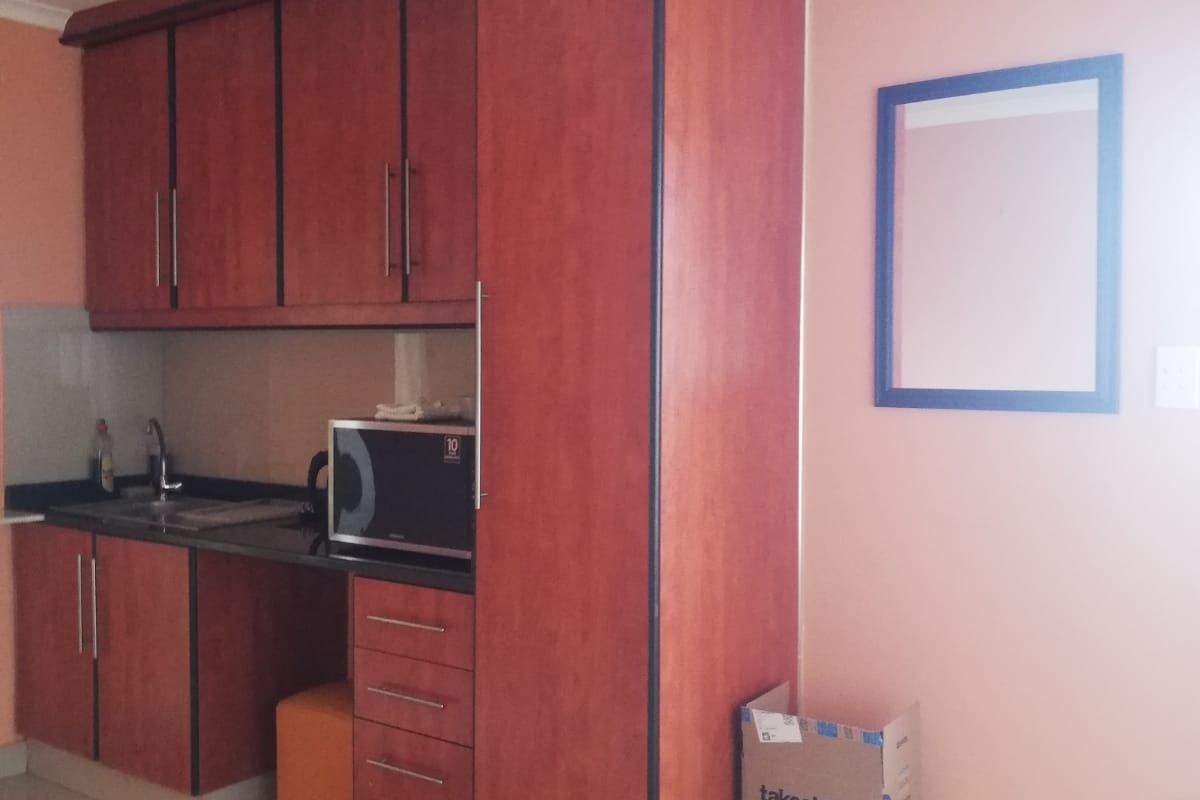 Compact kitchen area featuring wood-finish cabinetry, dark laminate countertops, and tiled flooring, providing a functional prep space within the cottage.
