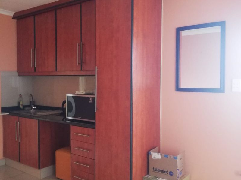Compact kitchen area featuring wood-finish cabinetry, dark laminate countertops, and tiled flooring, providing a functional prep space within the cottage.