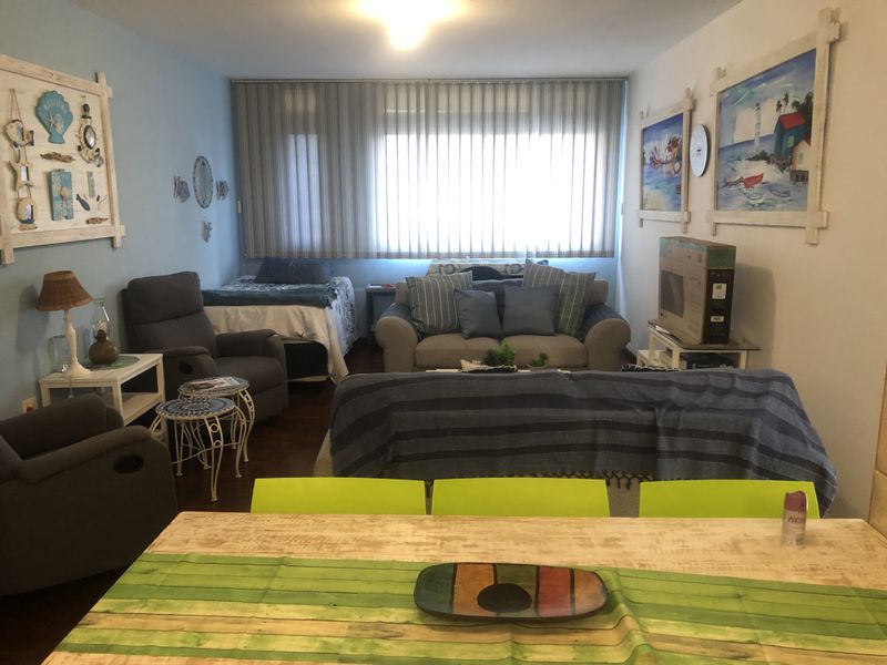 Open plan living and dining area featuring parquet flooring and large windows with vertical blinds.