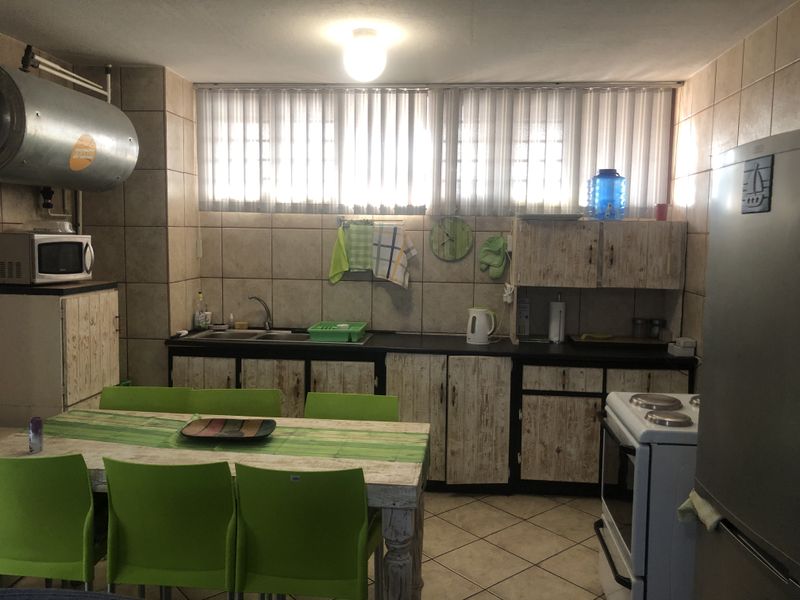 A functional kitchen featuring tiled walls and flooring, built-in cabinetry, a double sink, and an electric stove.
