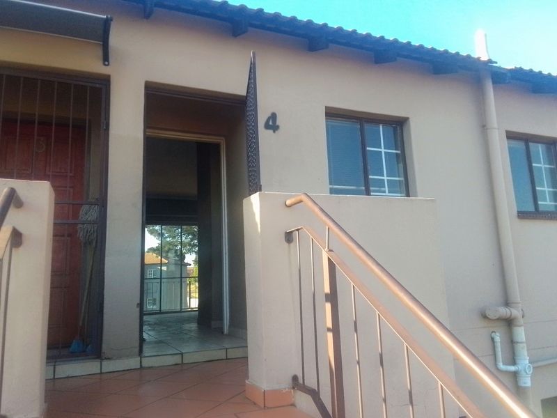 Front entrance view of a townhouse unit featuring a tiled landing, metal security gate, and external staircase with a metal handrail.
