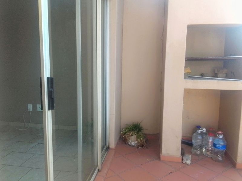 A covered patio area featuring a built-in braai and sliding glass door access to the interior living space.