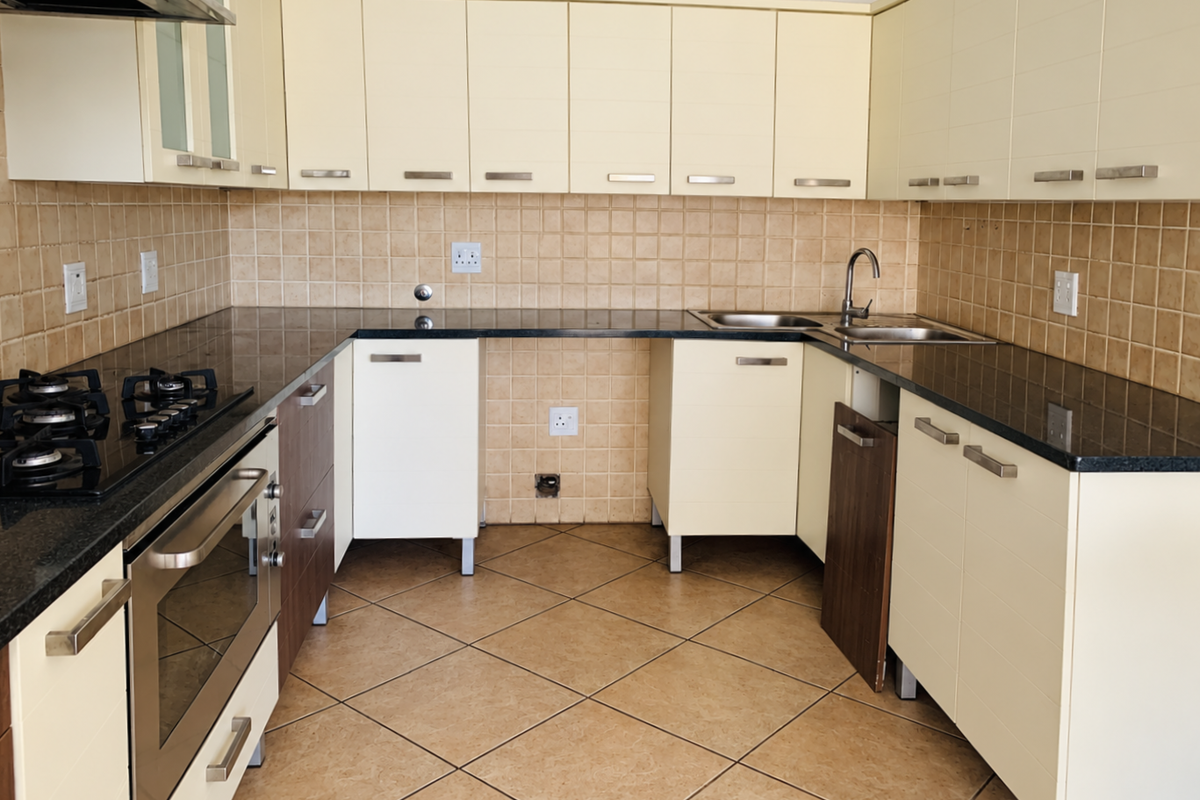 A functional kitchen featuring granite countertops, a gas hob, built-in oven, and tiled backsplash, currently requiring minor repairs to cabinetry.