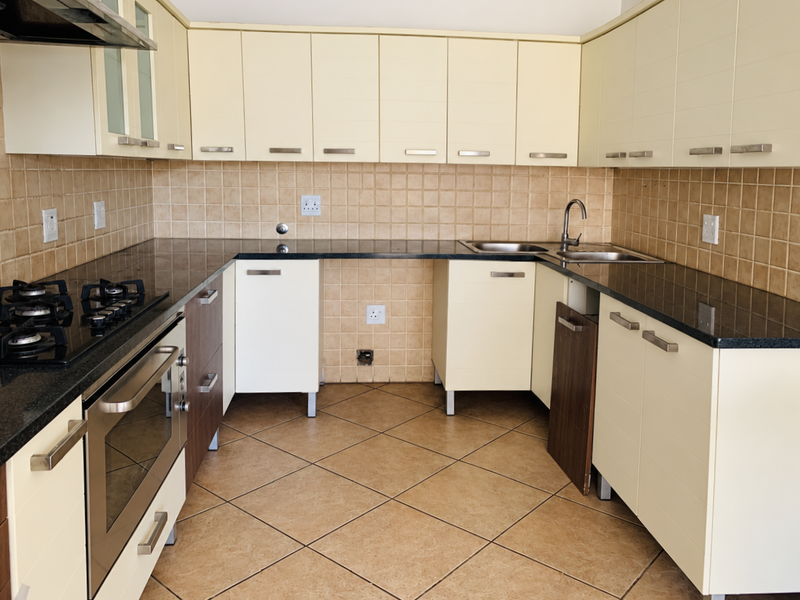 A functional kitchen featuring granite countertops, a gas hob, built-in oven, and tiled backsplash, currently requiring minor repairs to cabinetry.