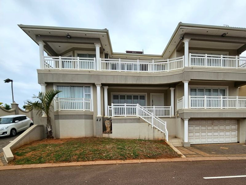A double-storey residential property featuring a paved driveway, integrated garage, and upper-level balconies with white railings.