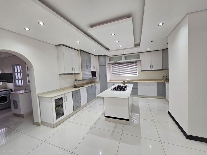 Modern kitchen featuring a central island with a gas hob, sleek white and grey cabinetry, recessed ceiling lighting, and polished tiled flooring.