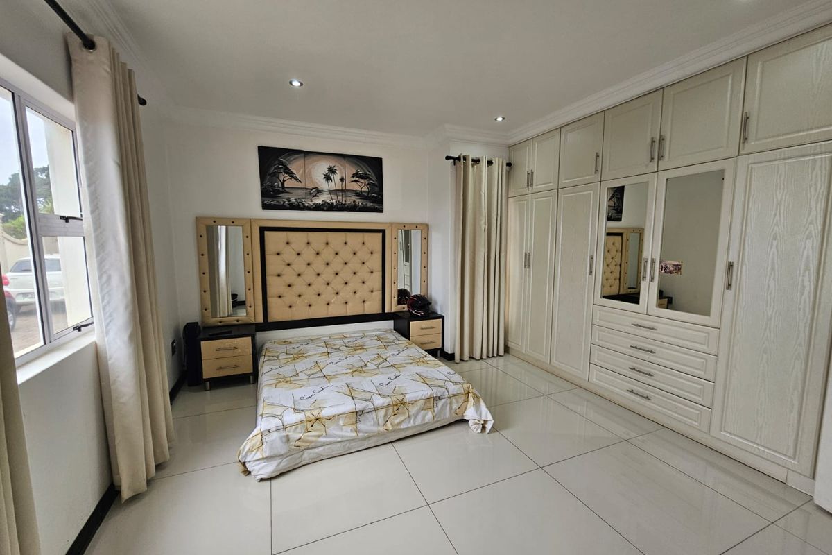 Spacious bedroom featuring large format floor tiles, extensive built-in cabinetry with integrated mirrors, and recessed ceiling lighting.