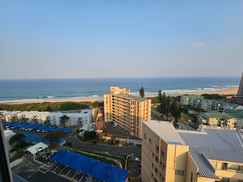 An elevated coastal view overlooking the ocean, surrounding residential apartment complexes, and parking areas.