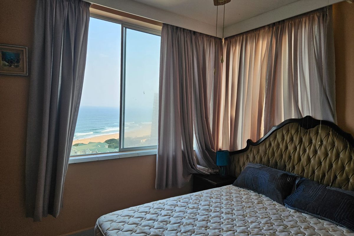 A bedroom featuring a large sliding window with ocean views and a ceiling fan.