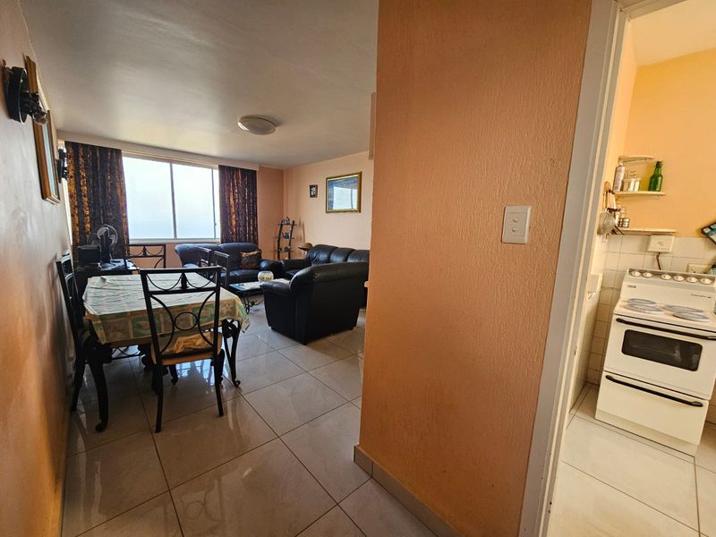 Open plan living and dining area with adjacent kitchen featuring tiled floors and a freestanding stove.