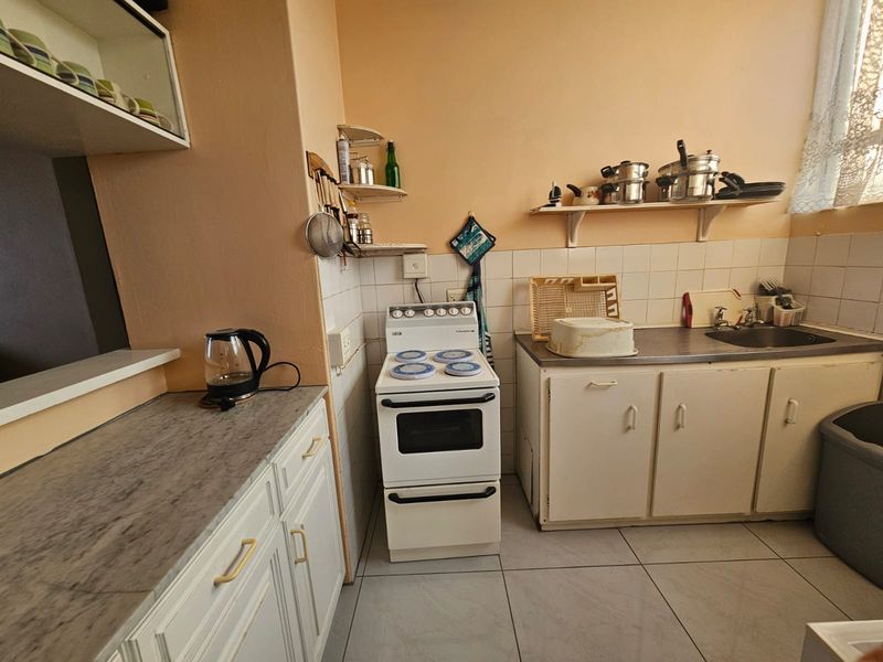 A functional kitchen featuring built-in cabinetry, a freestanding stove, tiled backsplash, and a stainless steel sink with ample counter space.