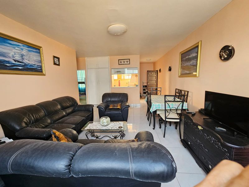 Open-plan living and dining area featuring tiled flooring, built-in storage cupboards, and a convenient serving hatch connecting to the kitchen.