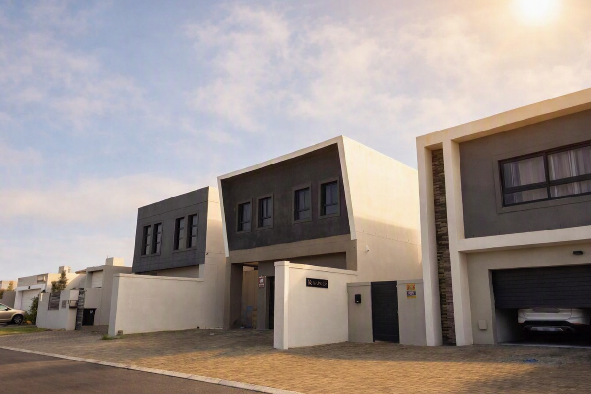 Modern contemporary residential facade featuring clean architectural lines, paved driveway, and integrated garage access within a secure estate setting.