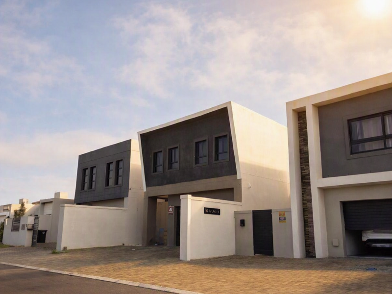 Modern contemporary residential facade featuring clean architectural lines, paved driveway, and integrated garage access within a secure estate setting.