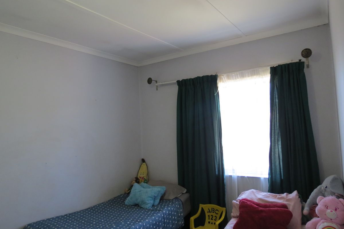 A standard bedroom featuring a window with a curtain rod and neutral wall finishes.