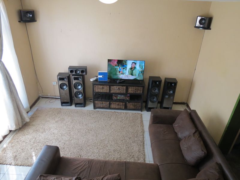 A living room featuring tiled flooring and wall-mounted speaker brackets, providing a functional space for entertainment.