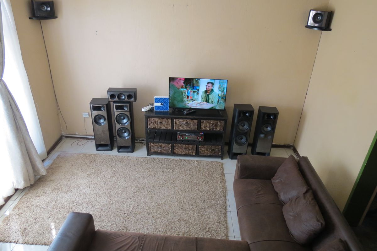 A living room featuring tiled flooring and wall-mounted speaker brackets, providing a functional space for entertainment.