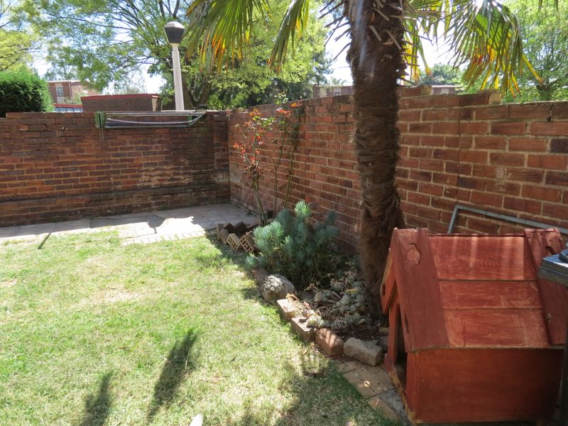 A private rear garden area featuring a brick boundary wall, paved section, and established garden bed.