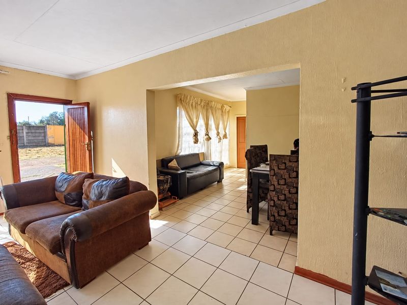 Open plan living and dining area featuring tiled flooring and direct access to the exterior through a timber door.