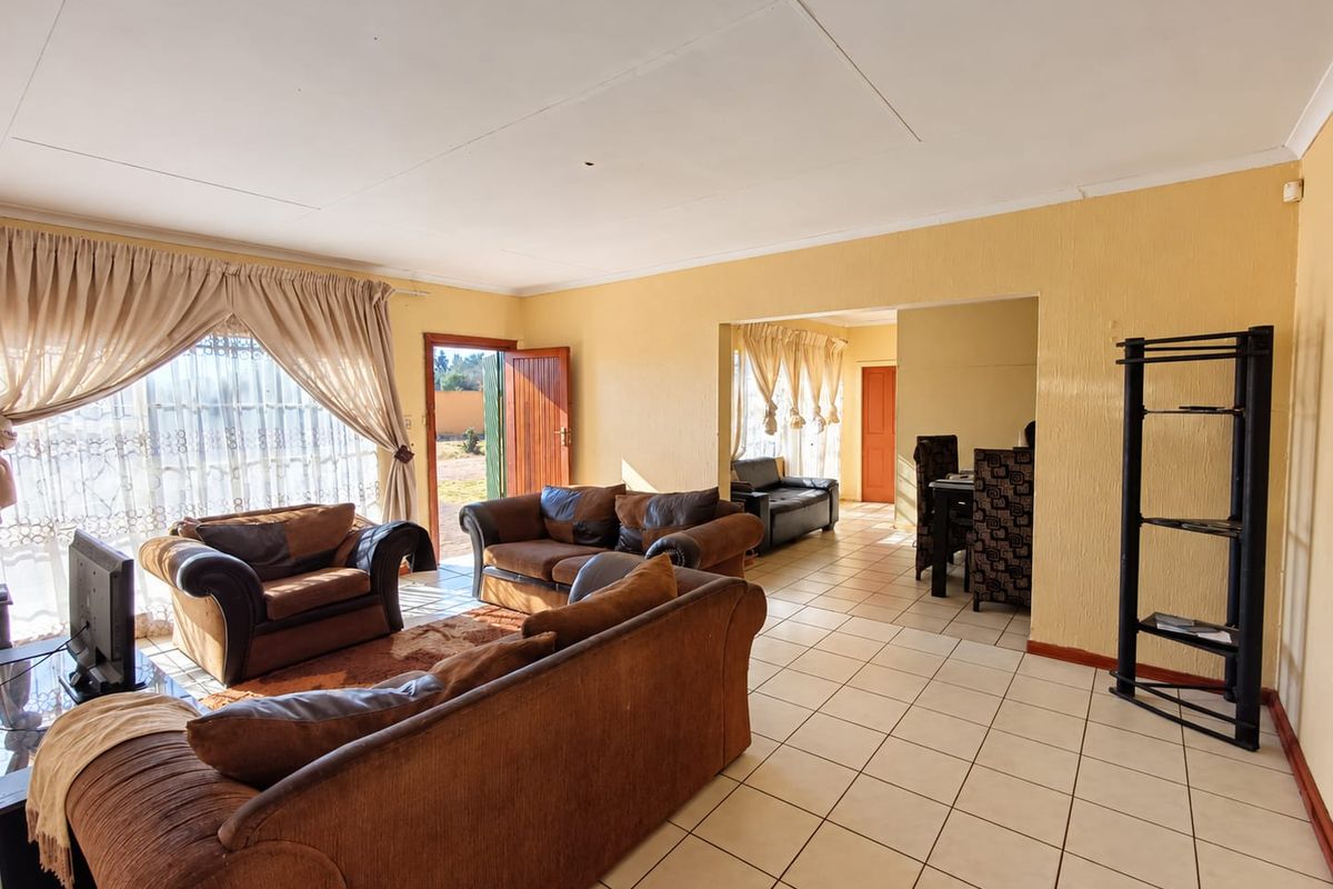 Spacious open-plan living and dining area featuring tiled flooring, textured walls, and direct access to the exterior through a sliding glass door.