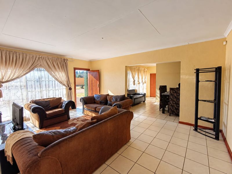 Spacious open-plan living and dining area featuring tiled flooring, textured walls, and direct access to the exterior through a sliding glass door.
