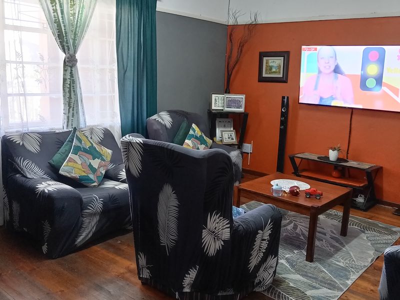 Living room featuring original hardwood flooring, coved ceilings, and a feature wall, with visible surface-mounted electrical wiring.