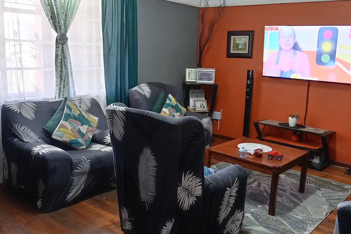 Living room featuring original hardwood flooring, coved ceilings, and a feature wall, with visible surface-mounted electrical wiring.