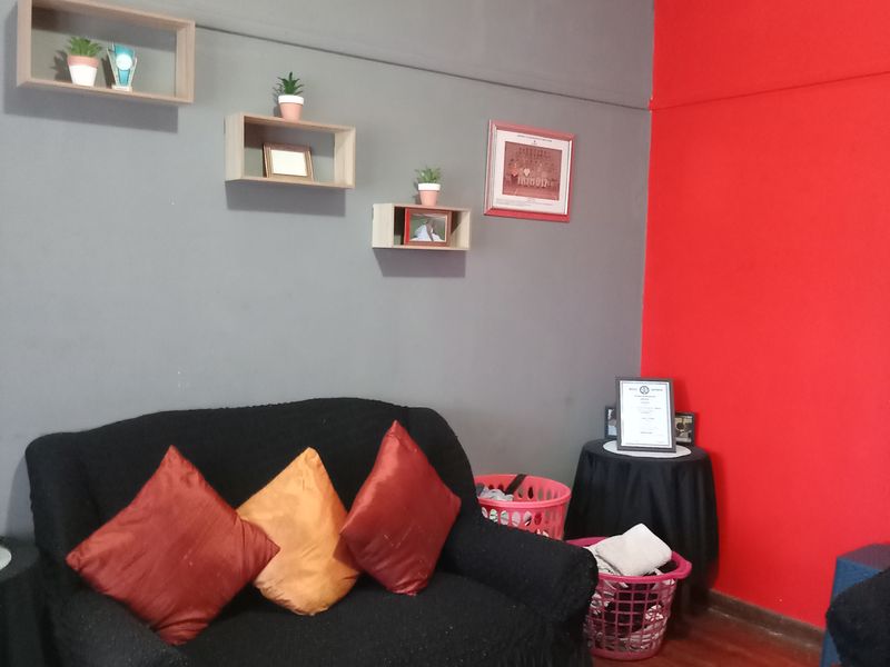 A living room featuring laminate flooring and a coved ceiling, currently styled with bold red and grey wall accents.