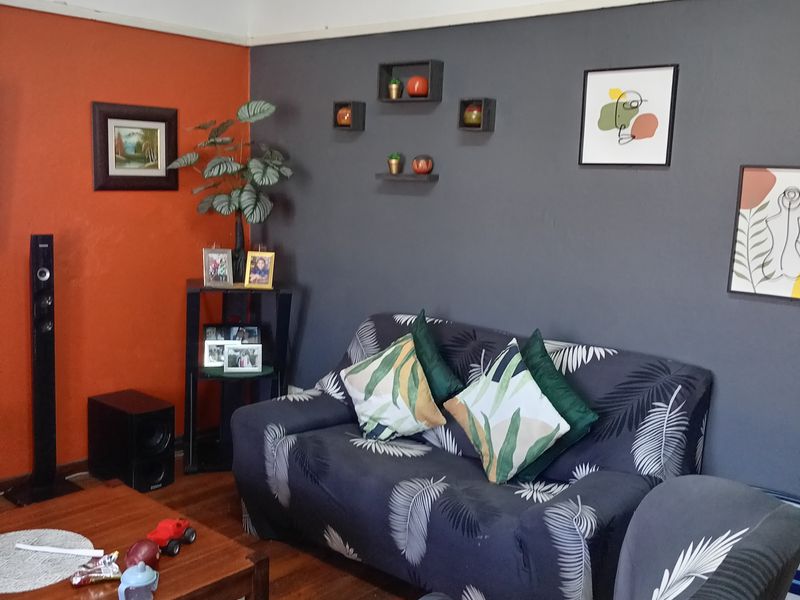 A living room featuring hardwood flooring, a coved ceiling, and a decorative picture rail, finished with a bold two-tone wall paint scheme.