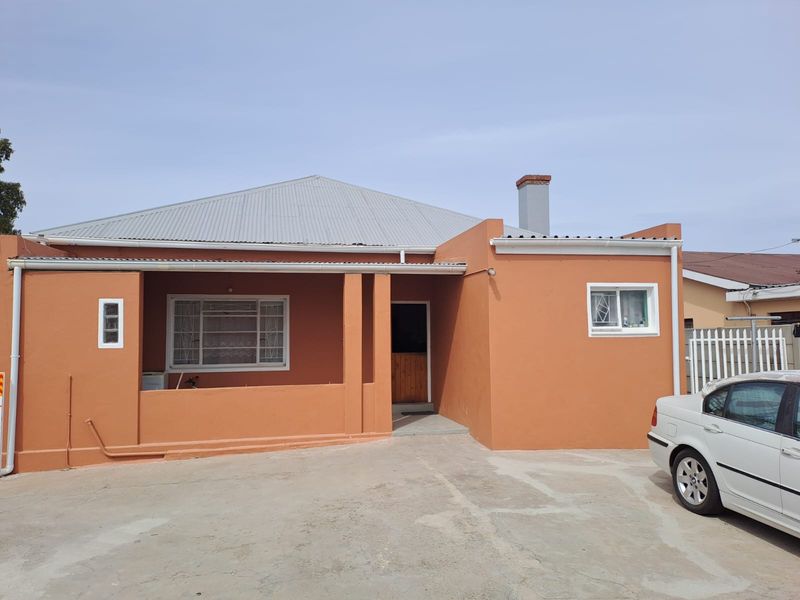 Front elevation of a single-story house featuring a corrugated metal roof, covered porch area, and a concrete driveway.