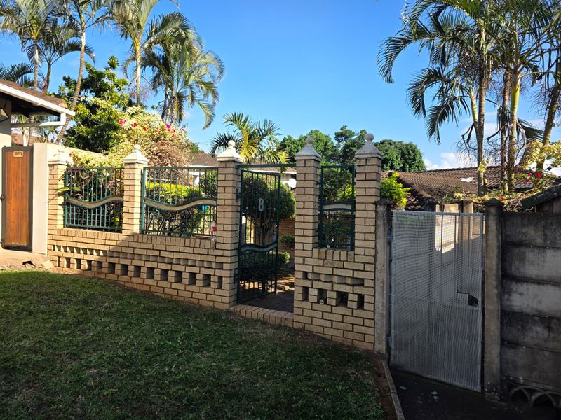Front entrance view of the townhouse featuring a brick boundary wall with decorative metal fencing and a secure pedestrian gate.