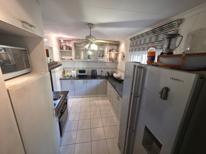 A functional kitchen featuring built-in cabinetry, granite countertops, a built-in oven, and tiled flooring, offering a practical layout for daily meal preparation.