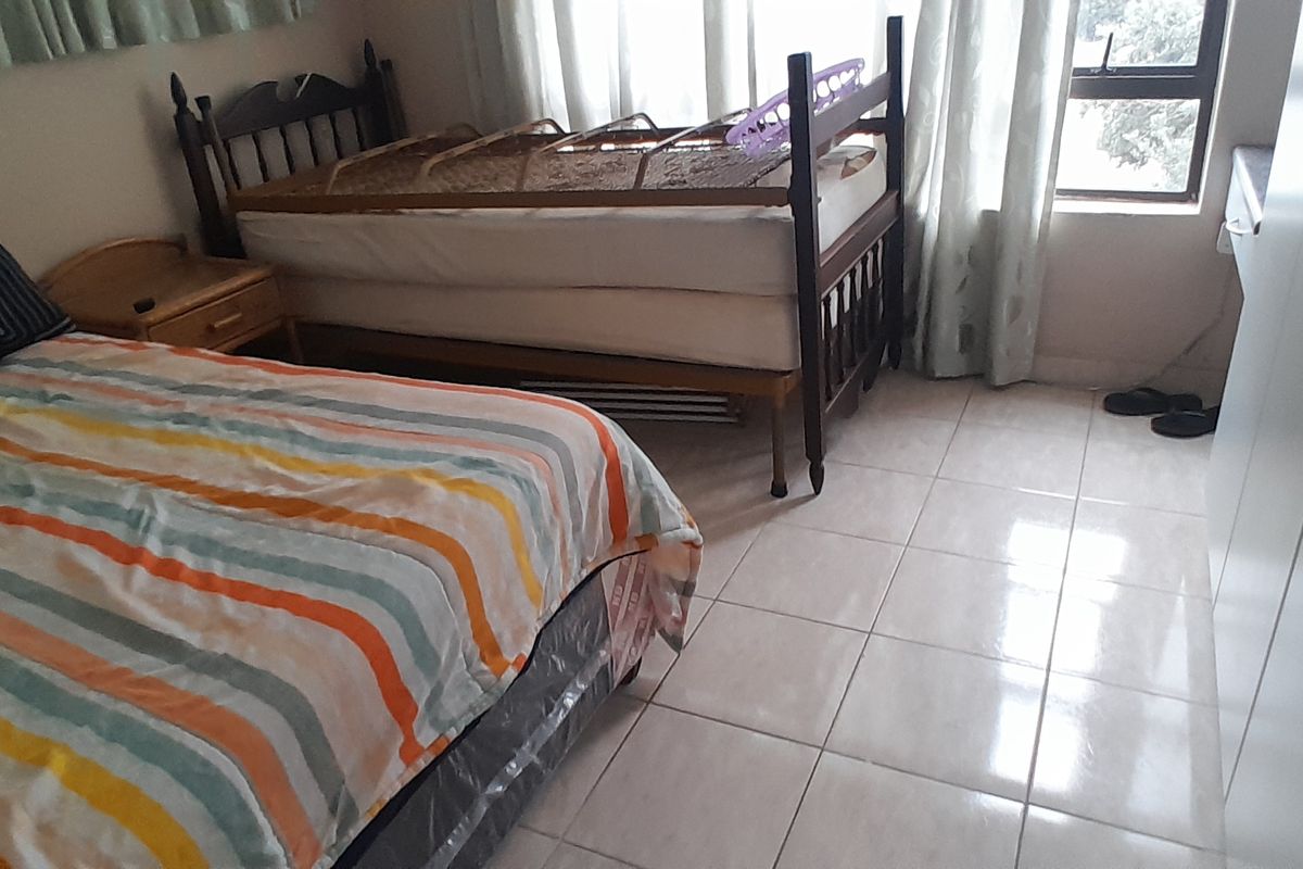 A bedroom featuring tiled flooring and built-in cupboards, providing functional storage space within the apartment.