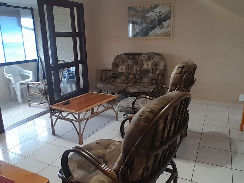 A spacious living area featuring tiled flooring and large sliding glass doors that provide access to an adjoining balcony and natural light.